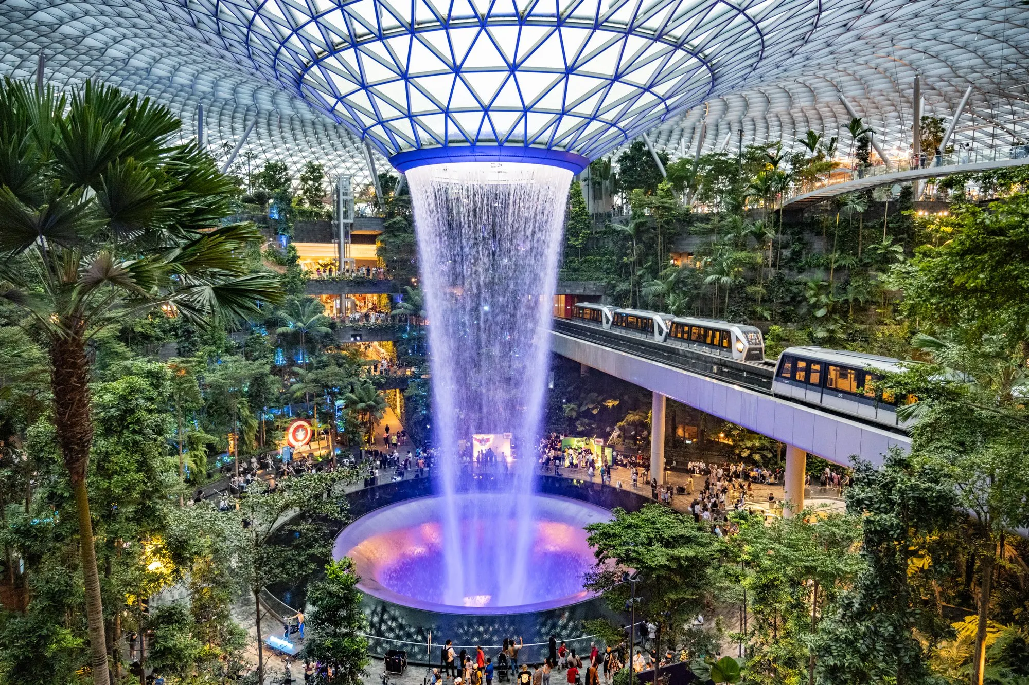 Jewel Changi Airport interior with the Rain Vortex, indoor gardens, and elevated skytrain.