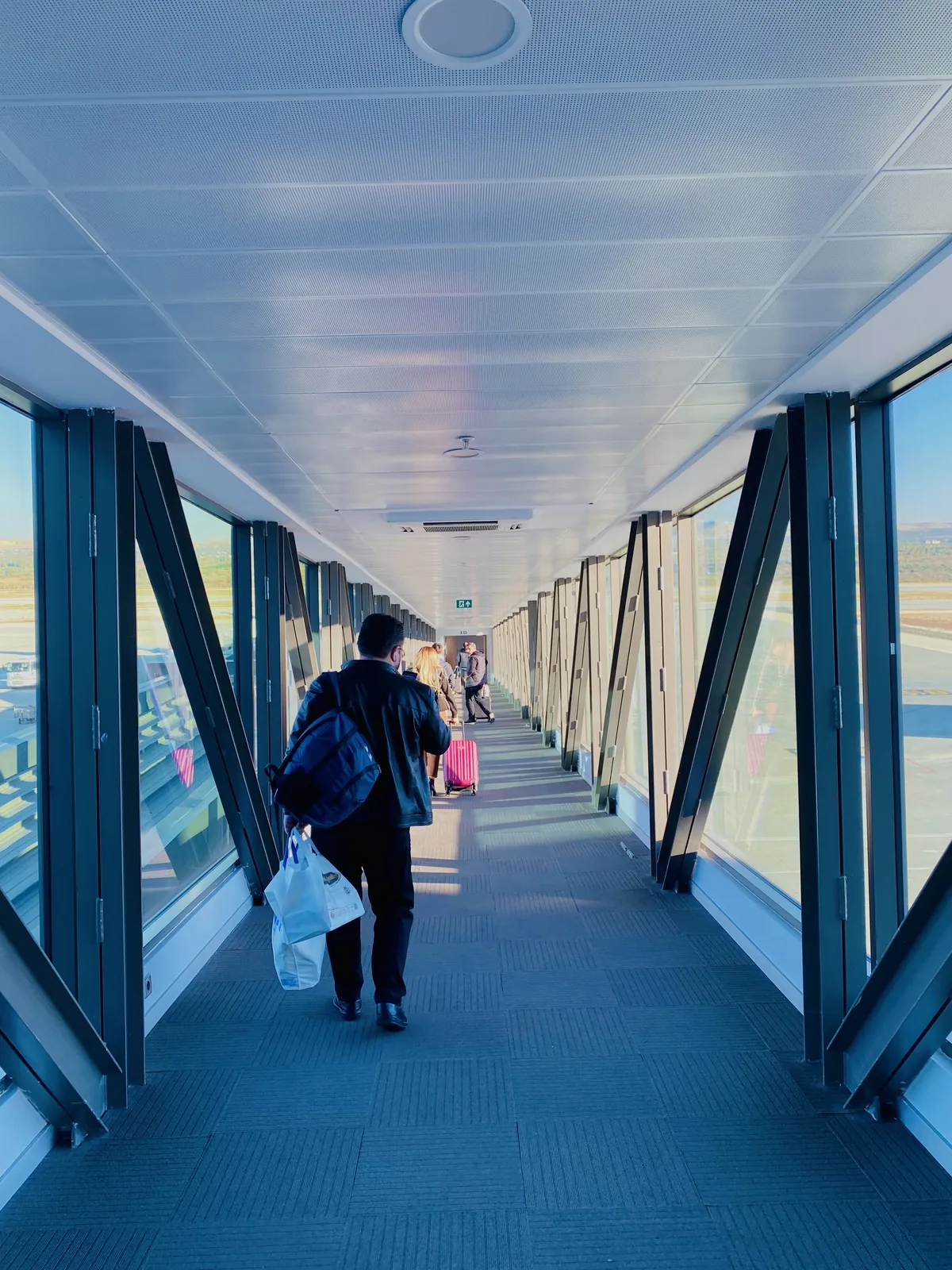 Gaziantep Airport passenger bridge with travellers and airfield views.