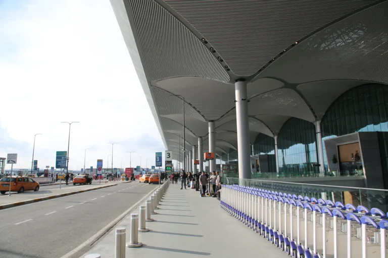 Istanbul Airport terminal exterior with roadway, passenger drop-off, and luggage trolleys.